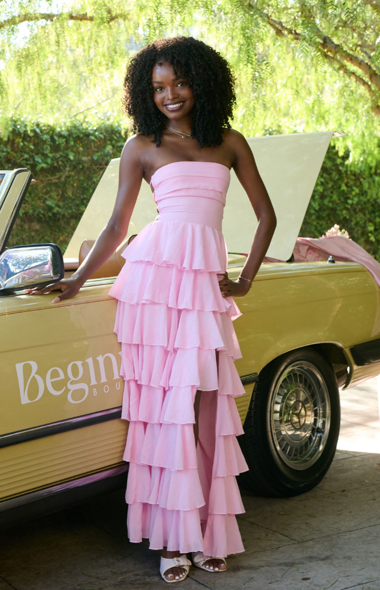 Full front view of a pink strapless maxi dress with a fitted pleated bodice and tiered ruffle skirt
