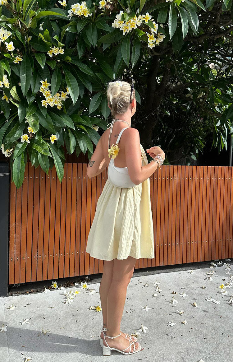 Rear view of a yellow halter mini dress showing the tie-neck detail and flowy gathered skirt