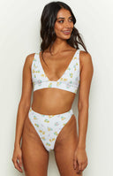 White bikini top with yellow and purple floral print, deep V-neck, and thick straps, with matching high-waisted bottoms