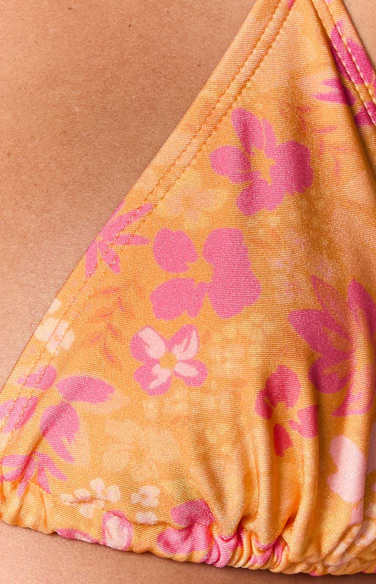 Close-up of the orange and pink floral print fabric with visible stitching and ruched bottom edge of the triangle bikini top