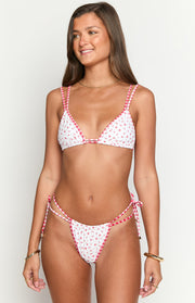 High-cut white bikini bottoms with red floral print, red gingham trim, and double tie-sides