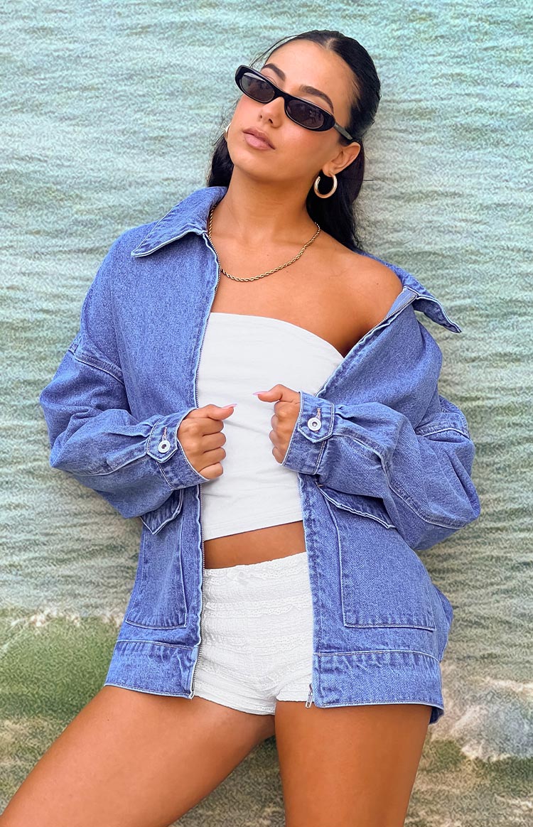 Girl wearing blue denim jacket with white tube top and micro shorts.