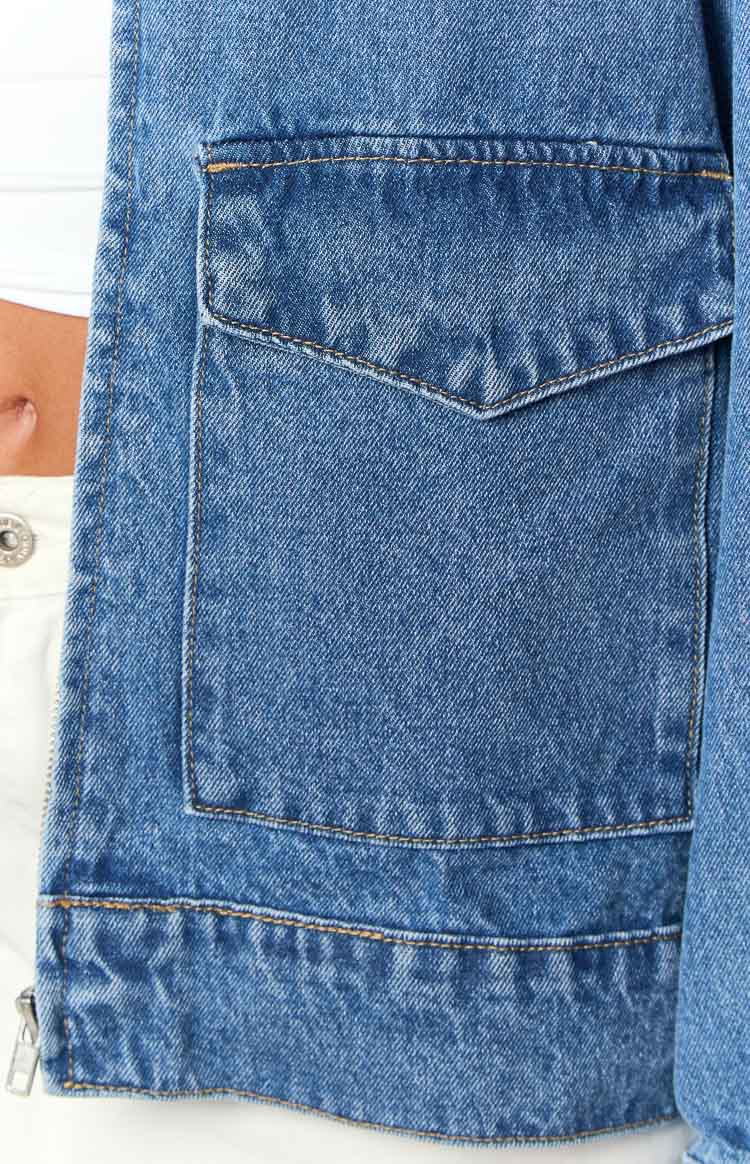 Mid wash denim bomber jacket with a large front patch pocket, pointed flap, and orange contrast stitching