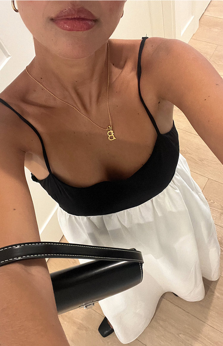 Close-up of the black bodice with thin spaghetti straps and gathered waist of the white maxi dress
