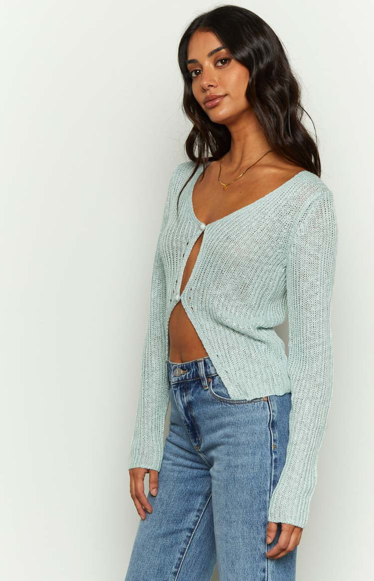 Side view of a light blue sheer knit long sleeve top with a V-neckline and single button closure