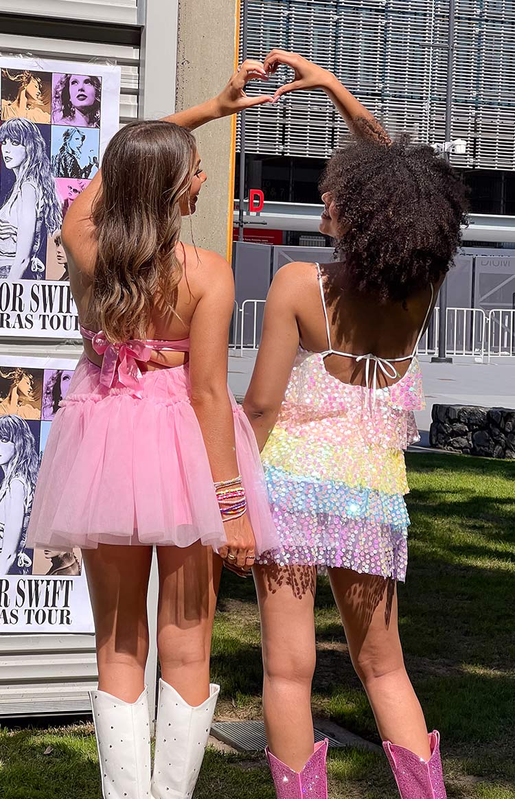 Rear view of a pink strapless mini dress showing the halter tie back, large bow, and tiered tulle skirt