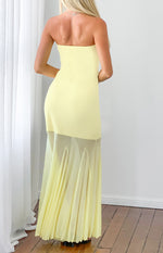 Rear view of a yellow strapless maxi dress with a sheer pleated asymmetrical overlay skirt