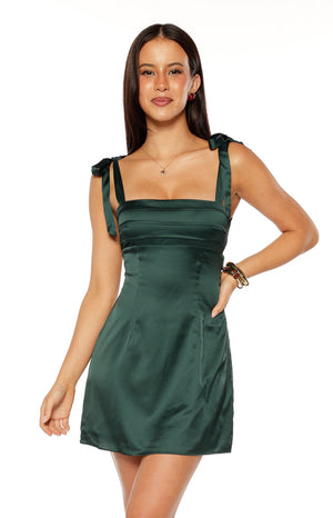 Our model wearing a dark emerald green satin mini-dress with a square neckline tie-up shoulder straps and horizontal seam detailing across the bust.