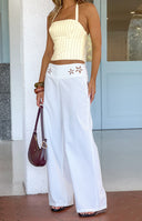 Close-up of the white wide leg pants showing floral cutouts on the front waistband