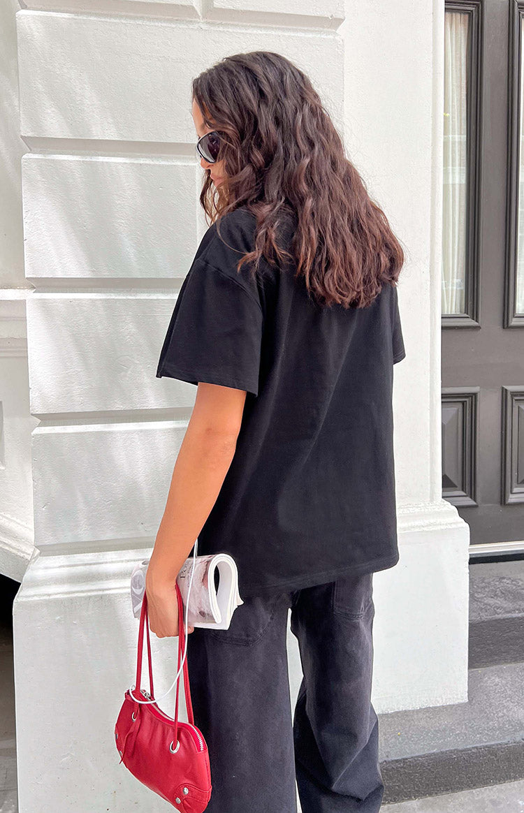 Rear view of a black oversized tee with short, loose sleeves and a relaxed, straight hem