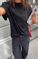 Angled view of the black plain tee, highlighting its crew neck, relaxed fit, and short sleeves
