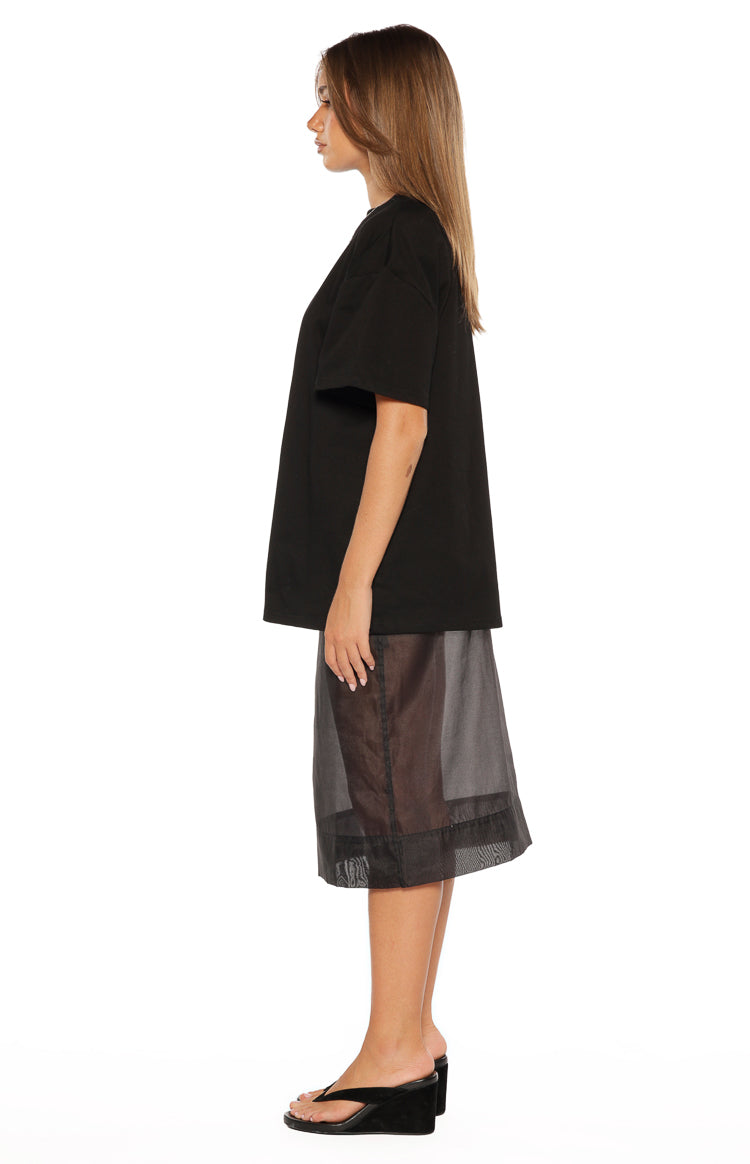 Side view showing the relaxed fit and dropped short sleeves of a black tee