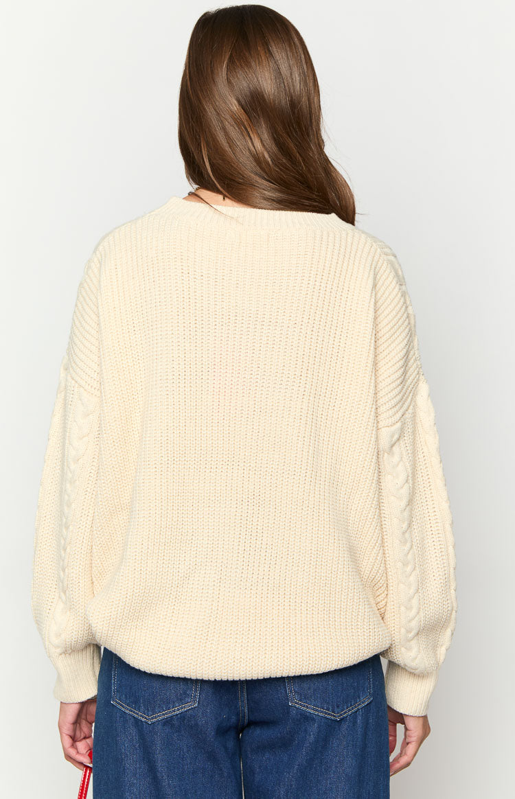 Rear view of a cream oversized round neck sweater with cable knit sleeves and ribbed body