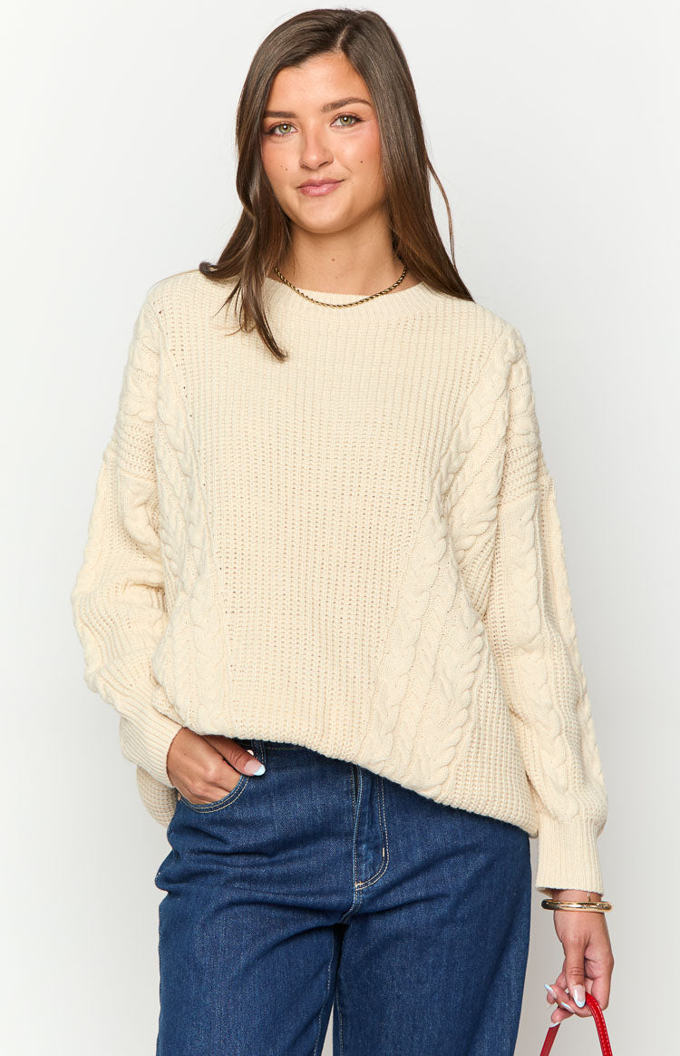 Cream oversized sweater with prominent cable knit pattern on the body and sleeves, ribbed cuffs and hem