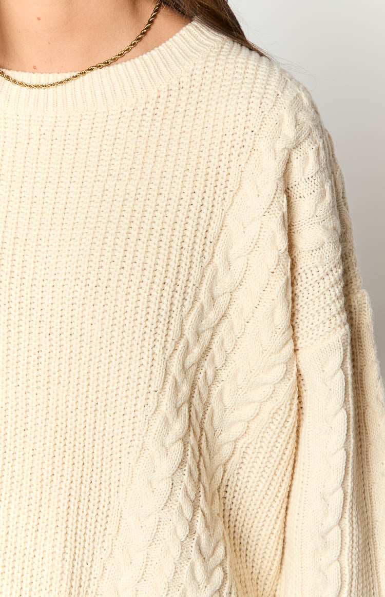 Detail shot of the cream knit sweater with a cable knit pattern on the shoulder and sleeve