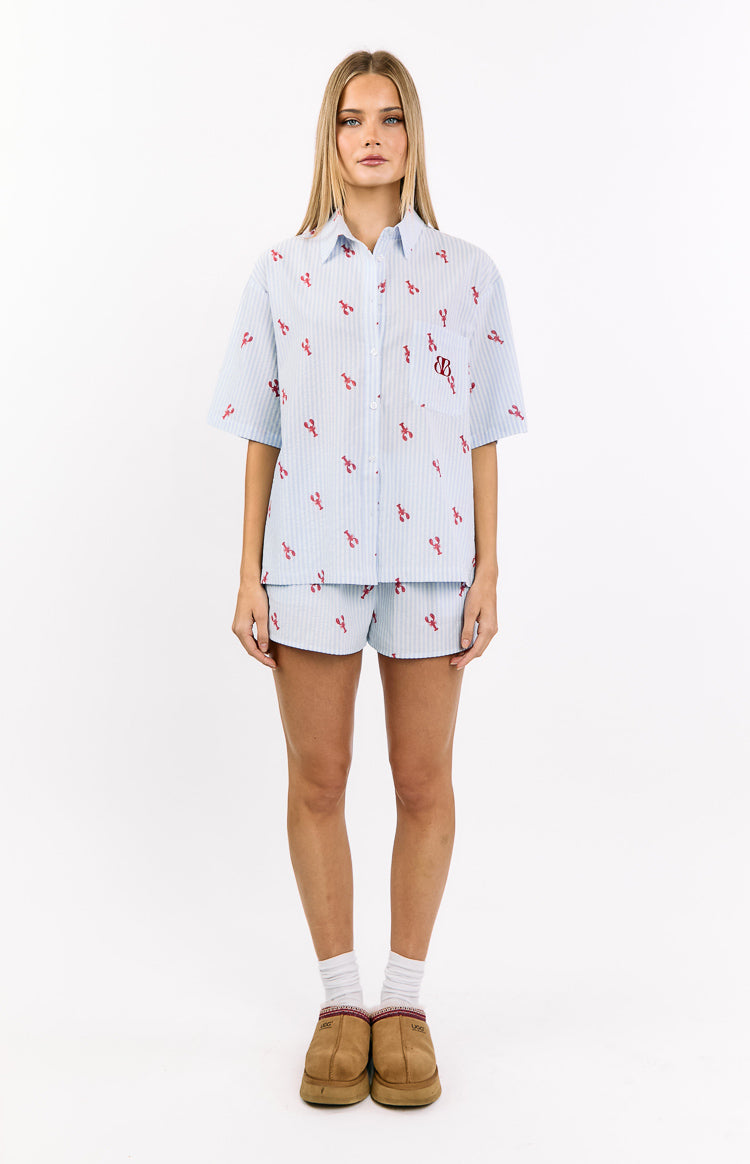 Front view of a light blue and white striped pajama shirt with red lobster print, collared neckline, button-front, and chest pocket with BB logo