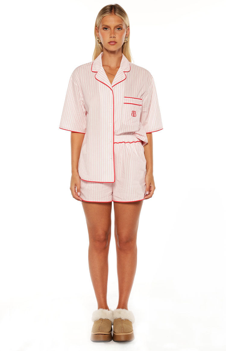 Pink and white striped pajama shorts with red piping, paired with a matching short sleeve button-up top