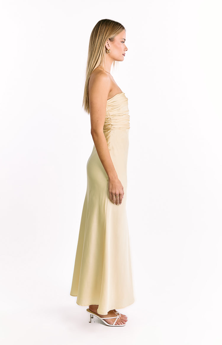 Side profile of a pale yellow strapless maxi dress showing the ruched bust and long flowing skirt