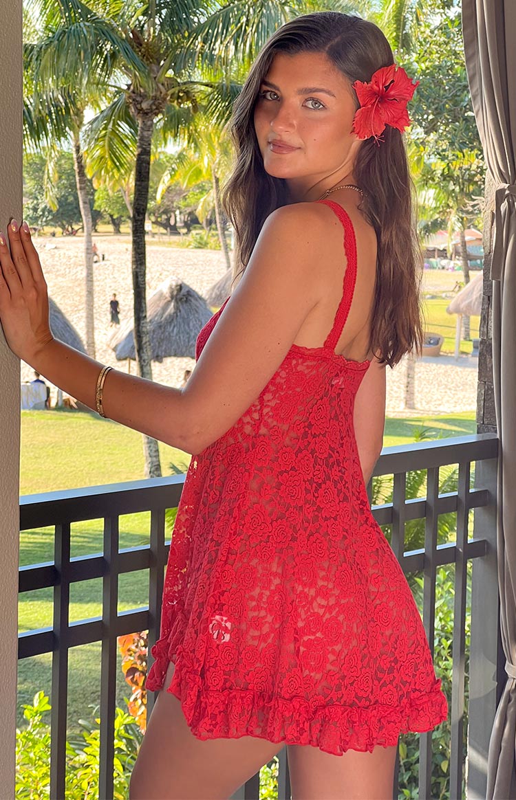 Red sheer floral lace mini dress with a ruffled asymmetrical hem and small bow detail on the neckline