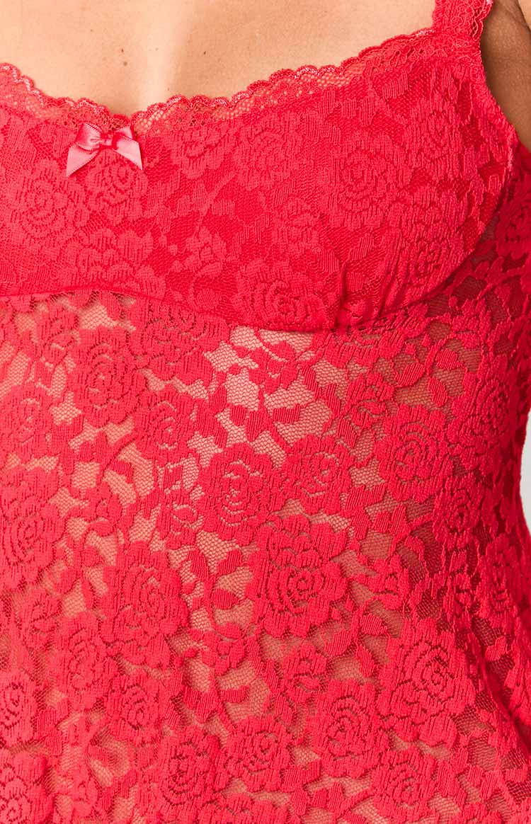Close-up of the red floral lace fabric with a sheer finish, scalloped trim, and a small pink bow detail on the neckline