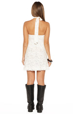 Rear view of a white lace mini dress with a halter neck tie and a ruffled hem