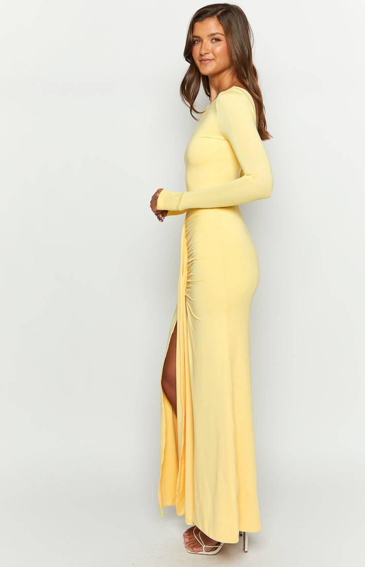 Side view of a yellow long sleeve maxi dress with ruched detailing and a high side slit