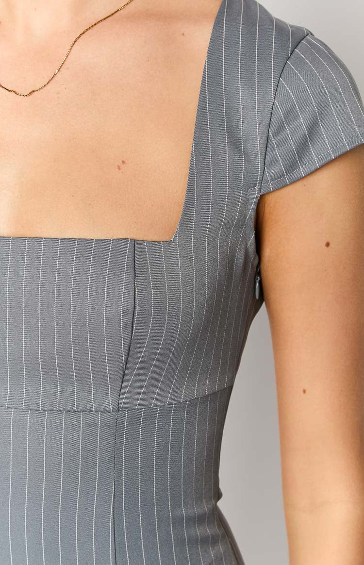 Detail shot showing the square neckline, cap sleeves, and side zipper of a grey pinstripe mini dress