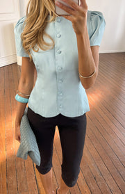 Blue organza top with a high round neckline, full button-up front, short puff sleeves, and scalloped hem
