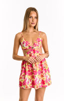 Yellow mini dress with a vibrant pink and orange floral print- featuring a sweet-heart neckline with a twisted front- thin spaghetti straps- and side cut-outs at the waist. A delicate four-leaf clover necklace and a bracelet are worn.