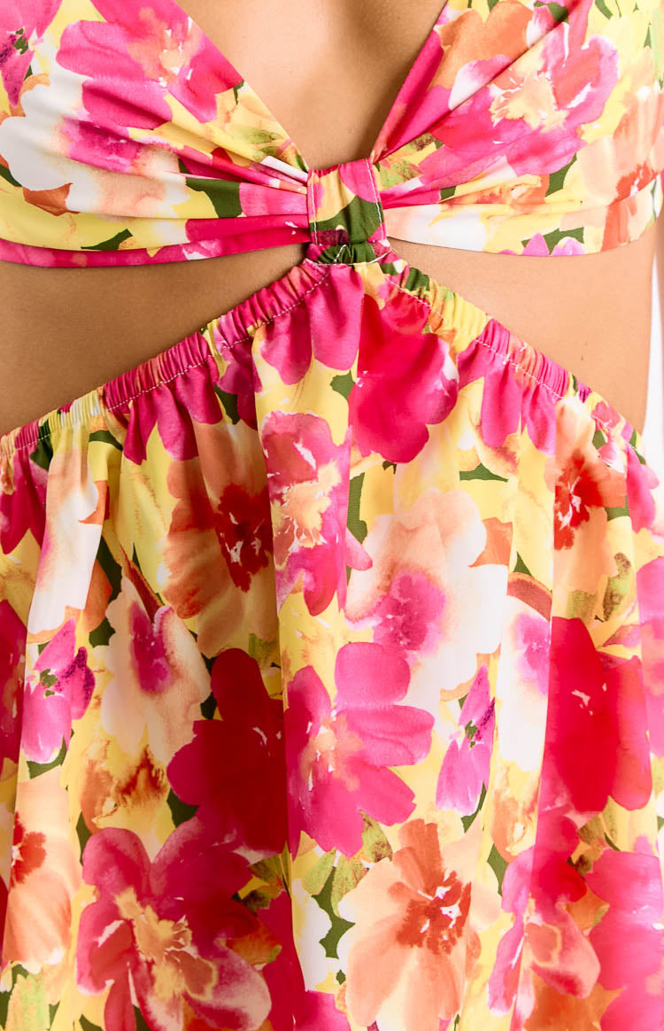 Close-up of the yellow floral print with pink and orange flowers, showing the twisted fabric waist detail and shirred skirt