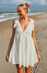 White mini dress with a deep V-neckline, tie-shoulder straps, and a tiered skirt design