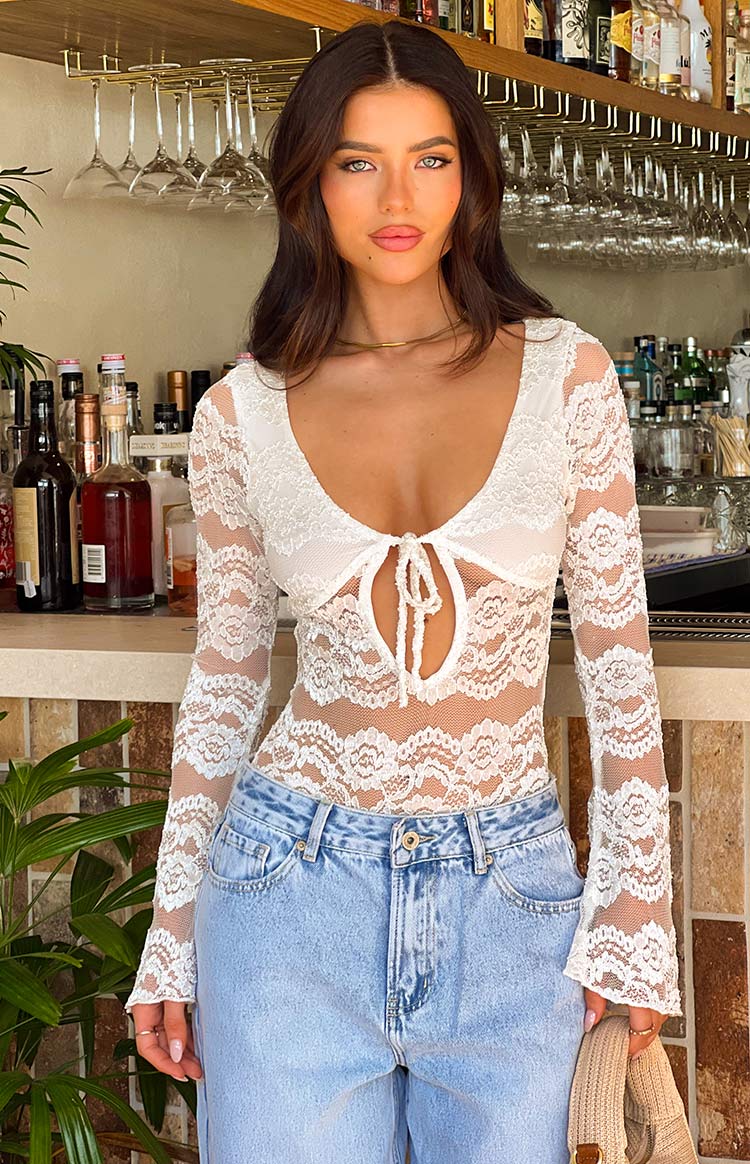 Front view of a white sheer lace bodysuit with a tie-front scoop neck and keyhole cutout