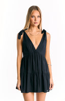 A tiered black mini dress with a plunging V-neckline and charming tie-shoulder straps- offering a sweet and casual style.