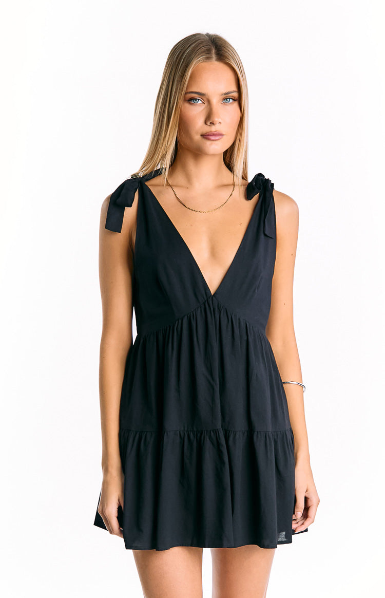 Black mini dress with a deep V-neckline, tie-shoulder straps, and a gathered tiered skirt