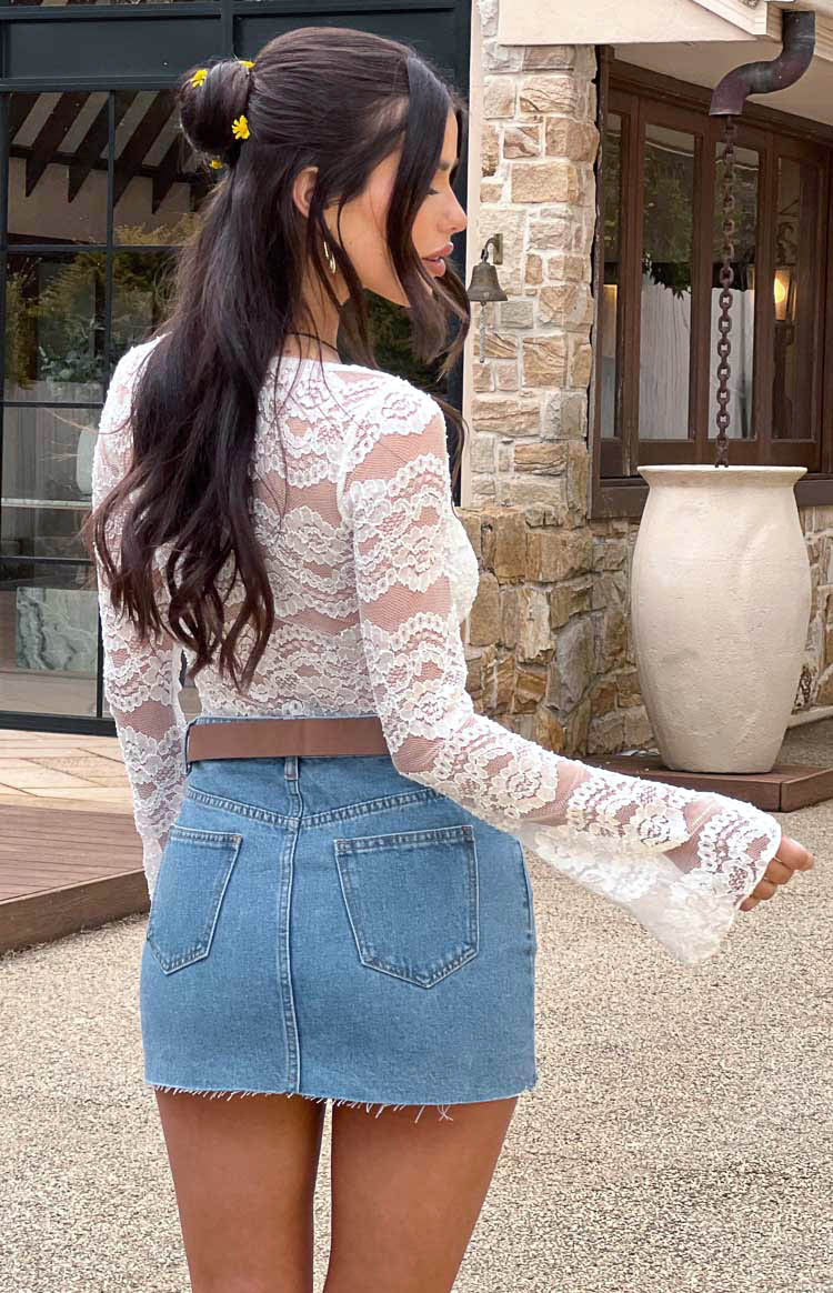 Rear view of the white lace bodysuit, highlighting the long sleeves with wide, flared cuffs and intricate floral lace