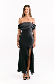 Black satin off-shoulder maxi dress with a ruched neckline and a high leg split with ruffle trim