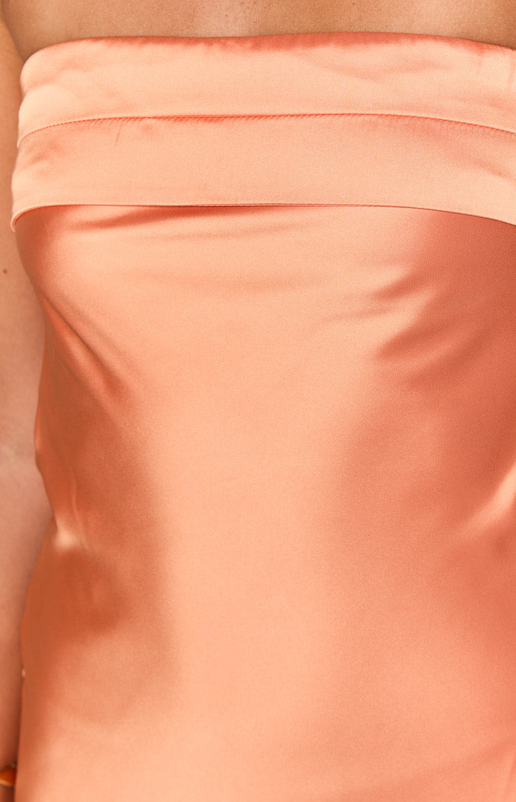 Close-up of the orange satin strapless mini dress showing the folded band at the neckline