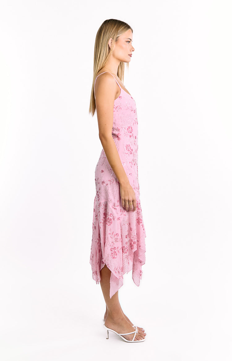 Side view of a pink sequin midi dress with thin spaghetti straps and a flowing handkerchief hemline