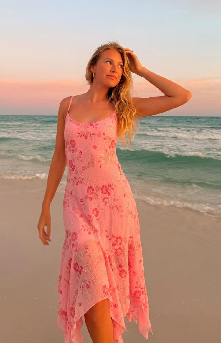Flowy pink sequin midi dress with thin spaghetti straps and an asymmetrical handkerchief hem