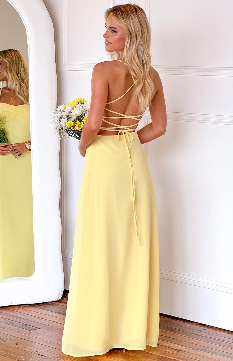 blonde girl wearing a yellow formal gown with an open back and lace up tie details