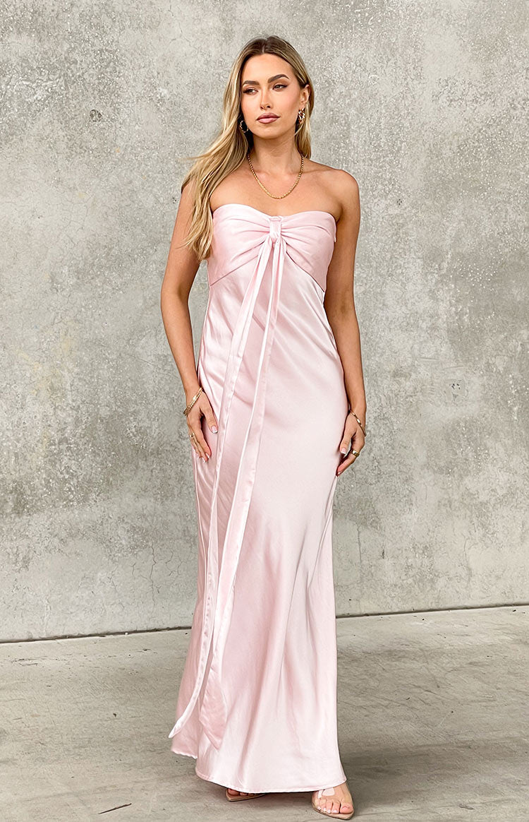 Pink satin strapless maxi dress with a gathered bust, central bow, and long flowing ties