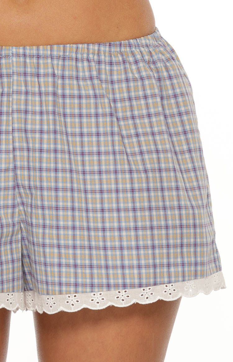 Detail shot of the blue plaid shorts with an elasticated waist and white scalloped eyelet lace trim