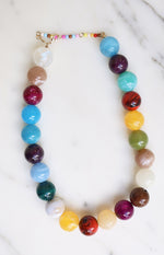 Multi-coloured necklace with large round marbled and solid beads in various shades, featuring a seed bead extender chain and