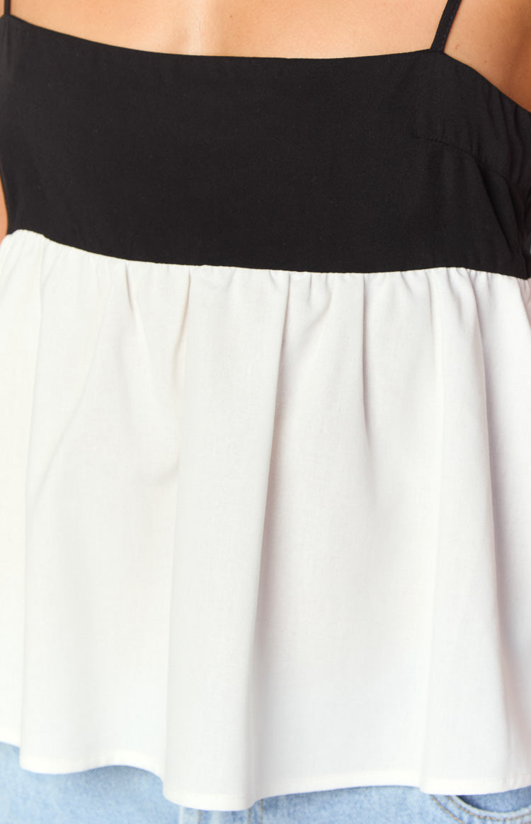 Close-up of the gathered white peplum hem flowing from the black bodice of a top