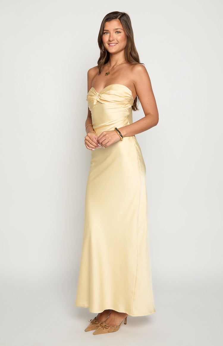 Side view of a pale yellow strapless maxi dress featuring a knotted bust and a long flowing skirt