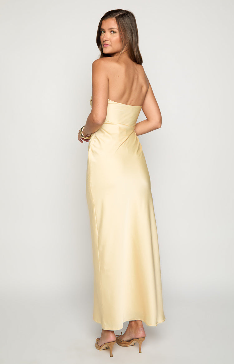 Rear-side view of a yellow satin strapless maxi dress with a fitted bodice and flowing skirt