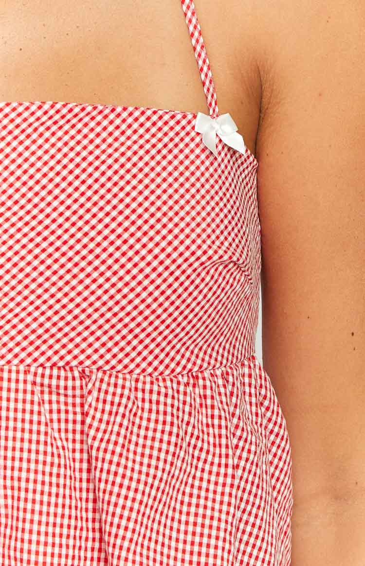 Close-up of the white bow detail on the red gingham strap and gathered waist of the halter top