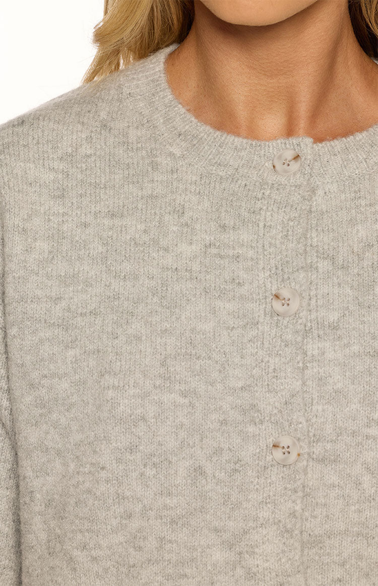 Close-up of the light grey knit cardigan showing the textured fabric and three light-coloured buttons