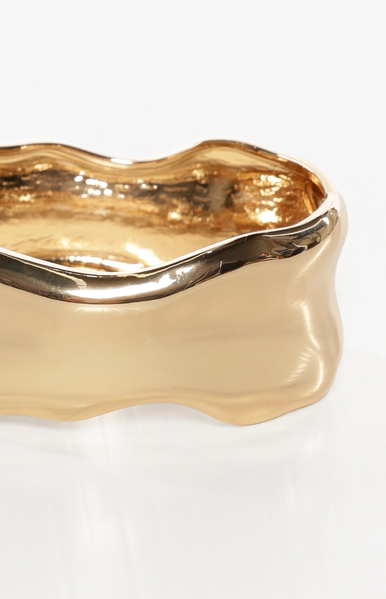 Close-up of a gold wavy bangle showing its shiny finish and textured interior
