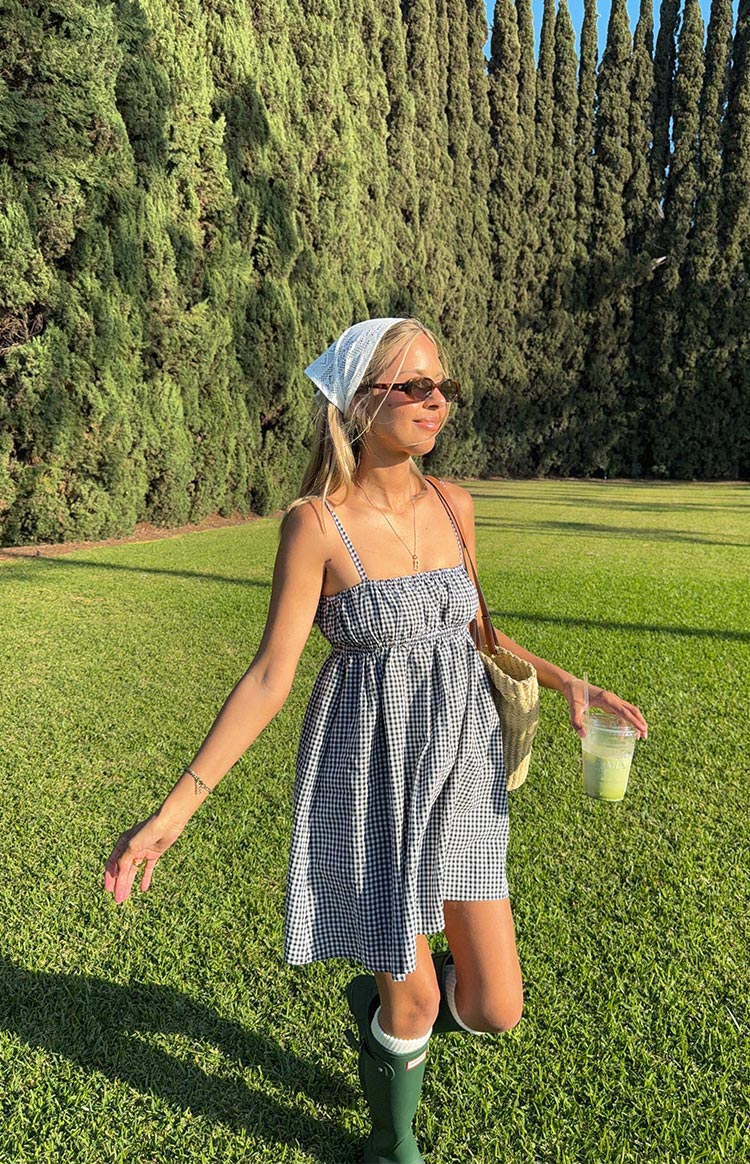 Angled view of a black gingham mini dress with a shirred bodice and a loose A-line skirt